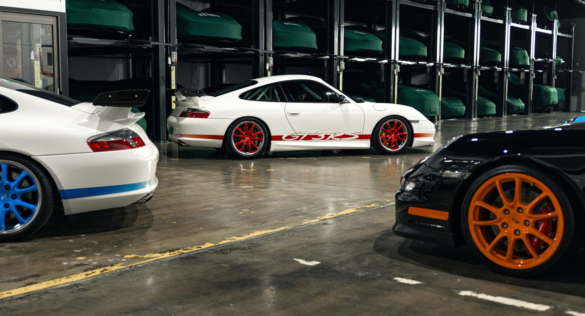 White Porsche 911 GT3 cars stored in a multi-level vehicle stacker at The Stable