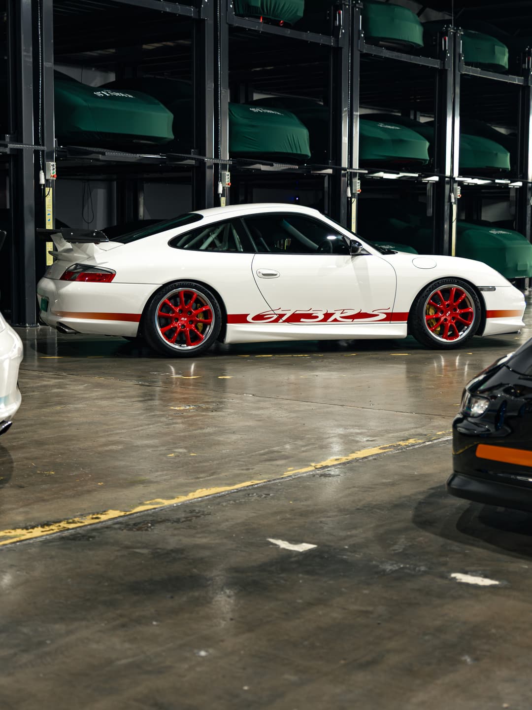 White Porsche 911 GT3 cars stored in a multi-level vehicle stacker at The Stable